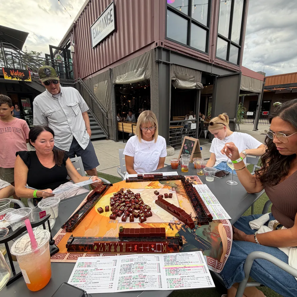 FoCo Mahjong players enjoying an outdoor game beside The Exchange sign
