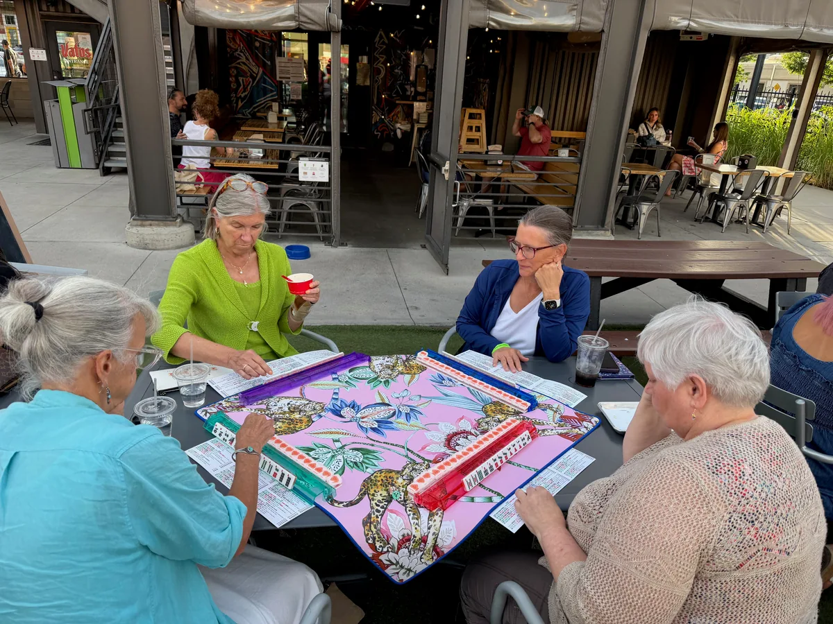 Four players focused on a colorful American Mahjong game at The Exchange