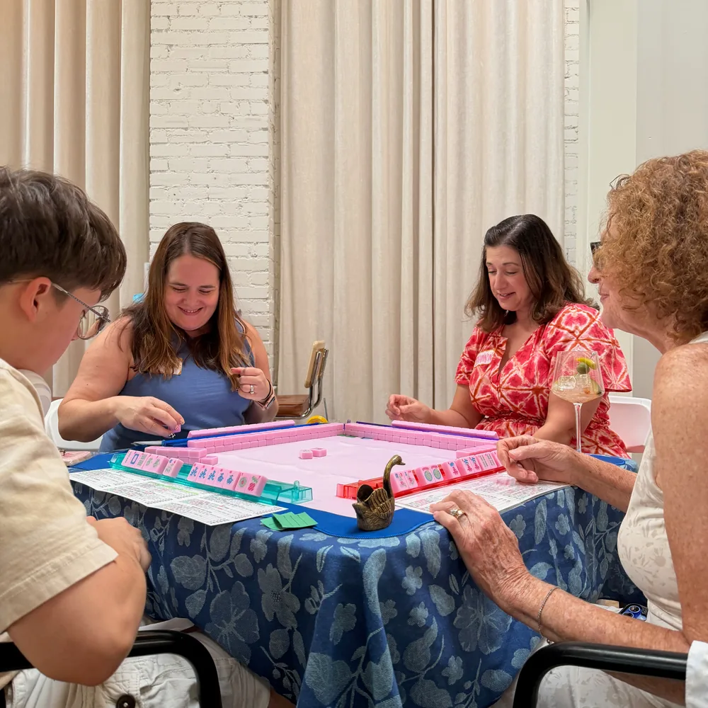 Four players smiling over a colorful American Mahjong game at The Neighbor